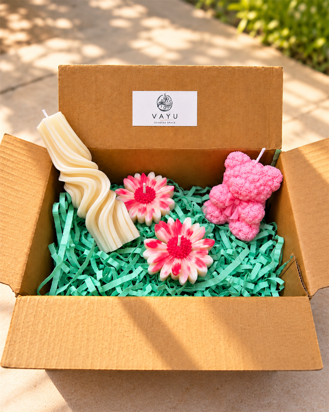Cream swirl pillar candle, pink rose-textured teddy bear candle, and two pink and white daisy candles in a Vayu gift box
