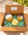 Two layered yellow and white glass jar candles and a cream daisy candle in a Vayu hamper box