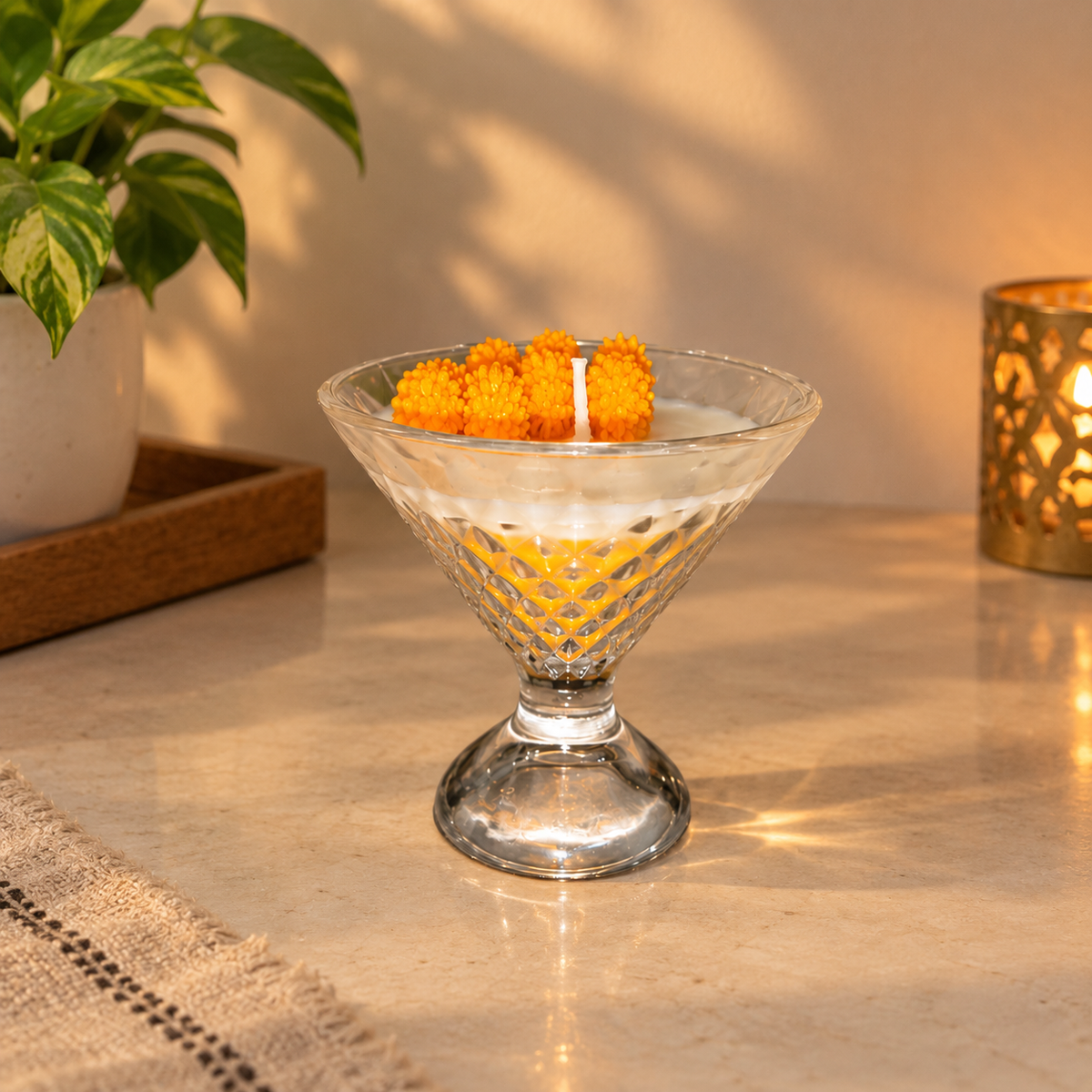 Dessert glass candle with orange wax flowers on a woven mat